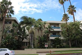 Los Angeles apartment for rent - A white car is parked in front of a building with palm trees.