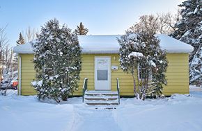 Grand Forks house for rent - A yellow house with snow on the ground and trees.
