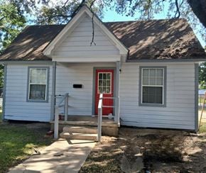Bay City house for rent - A small white house with a red door and a grey window.
