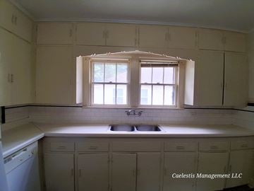 Bay City house for rent - A kitchen with white cabinets and a window above the sink.