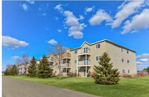 Moorhead apartment for rent - A large apartment building with a green lawn in front.