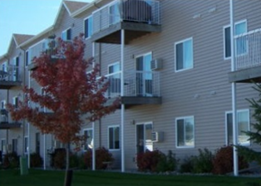 Moorhead apartment for rent - A tree with red leaves is in front of a building with balconies.