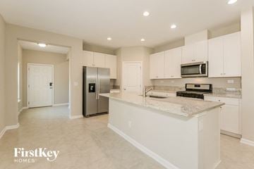 Yulee house for rent - a large kitchen with white cabinets and a counter top