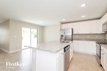 Winter Haven house for rent - a kitchen with white cabinets and a marble counter top