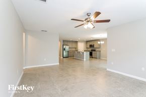 Winter Haven house for rent - A spacious empty room with a ceiling fan and a kitchen in the background.