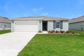 Winter Haven house for rent - a beige house with a white garage door and a lawn