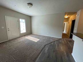 Boise apartment for rent - an empty living room with a white door and wood flooring