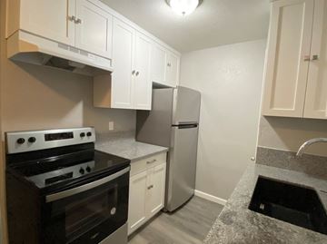 Merced house for rent - A kitchen with a stove, refrigerator, and cabinets.