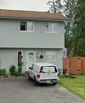 Anchorage apartment for rent - A white van is parked in front of a light blue house.