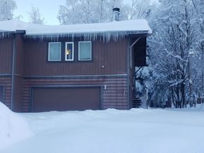 Eagle River apartment for rent - A house with snow on the roof and trees in the background.