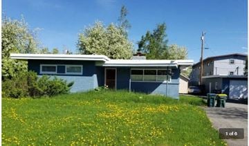 Anchorage apartment for rent - A blue house with a green lawn in front.