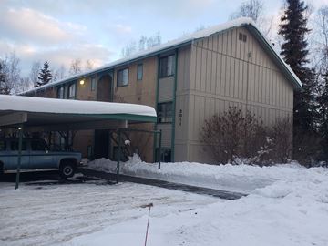 Anchorage apartment for rent - A building with a green truck parked in front of it.
