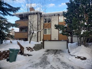 Anchorage apartment for rent - A snow-covered building with a green trash can in front.