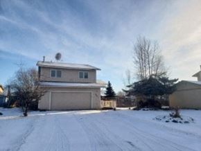 Anchorage house for rent - A house with a garage and a driveway covered in snow.