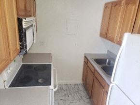Anchorage apartment for rent - A kitchen with a white refrigerator, white oven, and wooden cabinets.