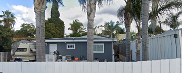 Vista apartment for rent - a blue house with palm trees and a white fence