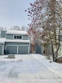 Anchorage apartment for rent - A house with a grey garage door and a tree with red leaves.
