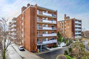 Brampton apartment for rent - A large red brick apartment building with a car parked in front.