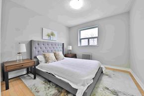 Mississauga apartment for rent - A bedroom with a large bed and a small table with a lamp on it.