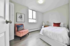 Mississauga apartment for rent - A bedroom with a white bed and a pink chair.