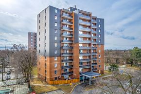 Mississauga apartment for rent - A tall apartment building with a parking lot in front.