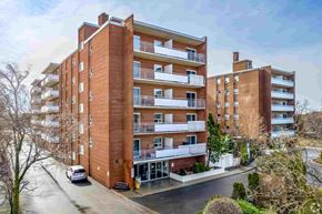 Brampton apartment for rent - A large red brick apartment building with a car parked in front.