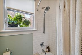 Tampa apartment for rent - A bathroom with a shower curtain and a window showing a view of a building and plants.