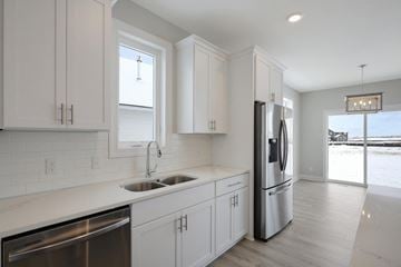 Hastings house for rent - a kitchen with white cabinets and a stainless steel refrigerator