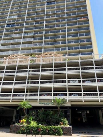 Honolulu apartment for rent - A large building with a balcony and a sign that says Island Colony.