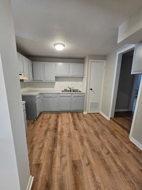 Bay City apartment for rent - A kitchen with white cabinets and a wooden floor.
