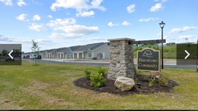 Fort Wayne apartment for rent - A sign for Bluestone Community stands in a grassy area in front of a row of houses.