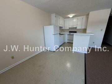 Wilson apartment for rent - A kitchen with white cabinets and appliances in a room with a carpeted floor.