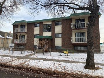 Edmonton apartment for rent - an apartment building with a yard and a tree in the snow