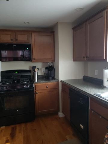 Rome apartment for rent - A kitchen with wooden cabinets and black appliances.