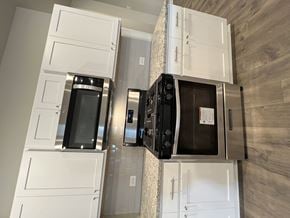 Duson house for rent - a kitchen with white cabinets and a counter top with microwave and ovens