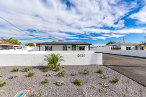 Phoenix apartment for rent - a home with a white wall and a driveway with plants in front of it