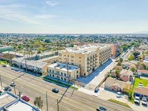 Inglewood apartment for rent - A large building is situated on a busy street with cars parked and driving by.
