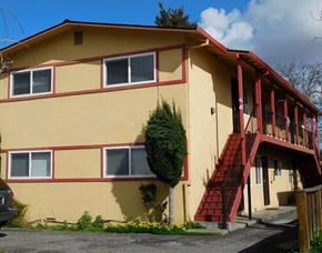 San Jose apartment for rent - a yellow house with red stairs and a tree in front of it