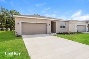 Bartow house for rent - a beige house with a driveway and a garage door