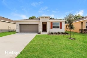 Bartow house for rent - a home with a lawn and a driveway and a garage door