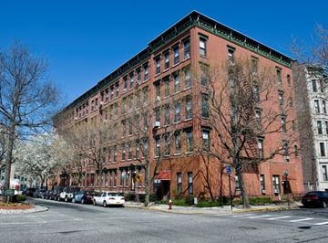 Hoboken apartment for rent - A large red brick building with a green trim around the windows and roof.