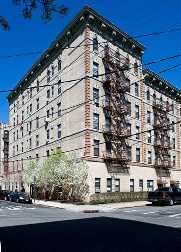 Hoboken apartment for rent - A large building with a brown brick facade and a green trim around the windows.