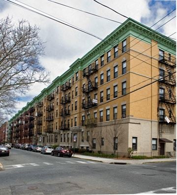 Hoboken apartment for rent - A row of brown and green buildings with cars parked on the street.