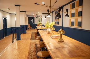 Hoboken apartment for rent - A long wooden table with a golden lamp on it and chairs around it.