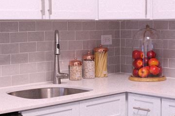 Hoboken apartment for rent - A kitchen counter with a sink, a jar of pasta, a jar of seeds, a jar of cereal, and a bowl of apples.