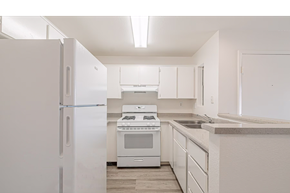 Rialto multi-family for rent - A white kitchen with a refrigerator, oven, and cabinets.