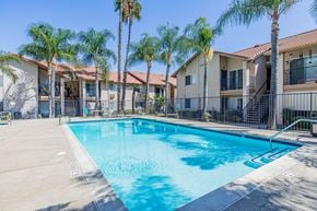 Rialto multi-family for rent - A swimming pool surrounded by palm trees and apartment buildings.