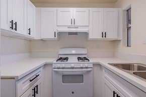Rialto multi-family for rent - A white kitchen with a stove and cabinets.
