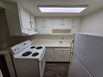 Vallejo apartment for rent - A small kitchen with white cabinets and a stove top oven.