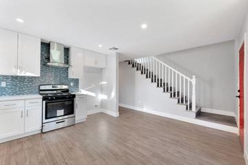 Canoga Park apartment for rent - a kitchen with white cabinets and a stove and a staircase